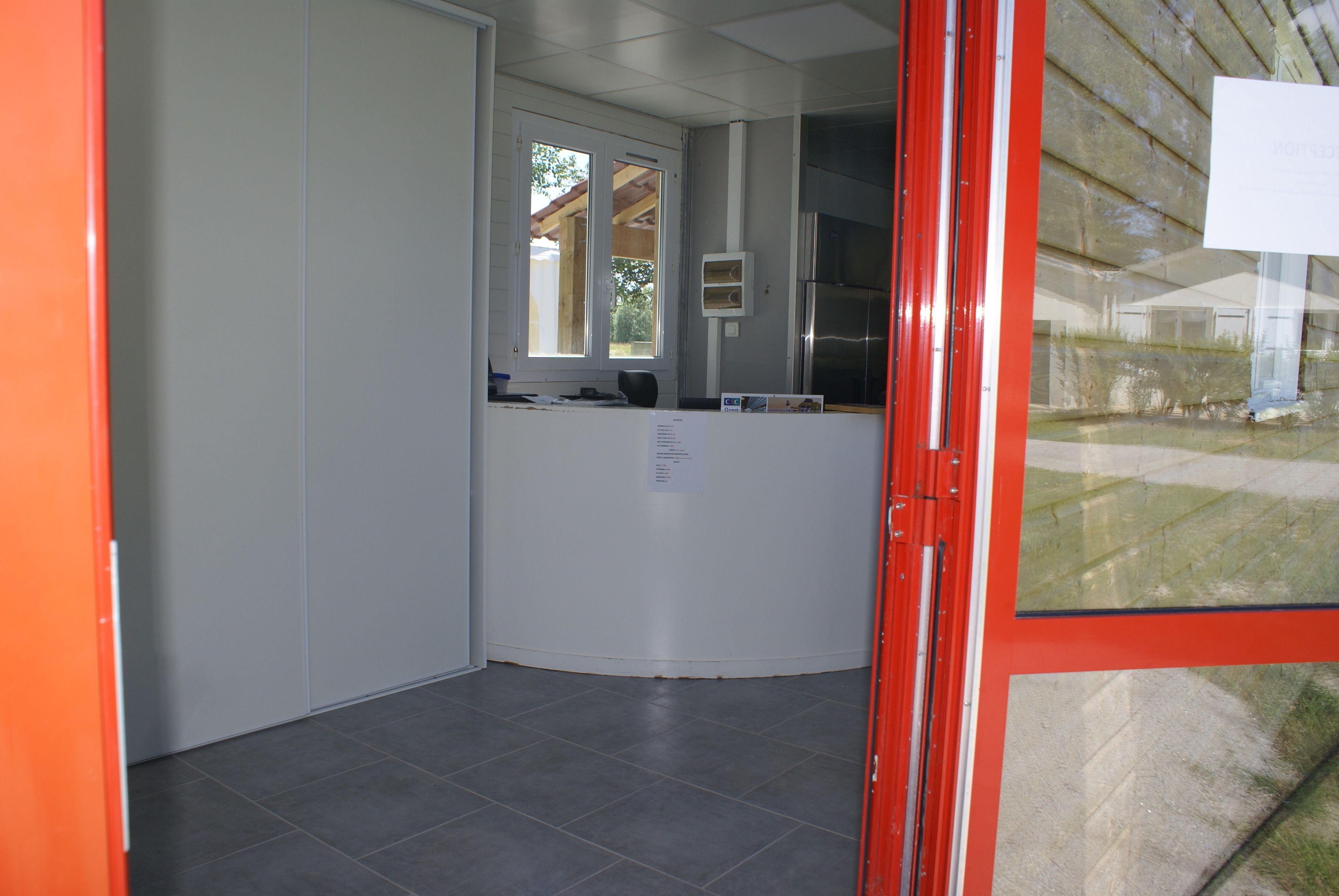 Un espace d’accueil comprenant un comptoir, une fenêtre et une porte.