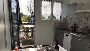 A kitchen with a dining table set for two, a bottle of wine, and a pitcher of water. - Les Gites De Montmartre (Le Perrier)