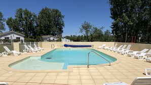 A swimming pool with white lounge chairs and a blue cover. - Les Gites De Montmartre (Le Perrier)