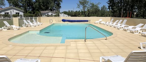 Una piscina al aire libre de temporada, sillones reclinables de piscina