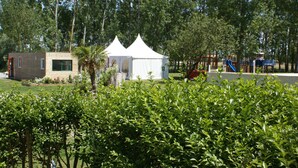 A small building with a white tent-like structure in the background, surrounded by greenery and trees. - Les Gites De Montmartre (Le Perrier)