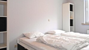 A bedroom with a bed, white bedding, a wardrobe, and a mirror. - Kompas 1 0102 (Nieuwpoort)