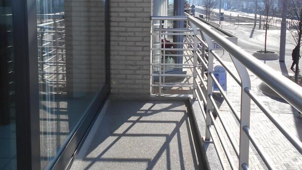 A modern building with large windows, a brick facade, and a metal railing overlooking a snowy landscape. - Kompas 1 0102 (Nieuwpoort)