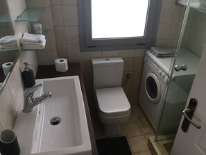 A compact bathroom with a sink, toilet, and washing machine. - Cozy Flat With Acropolis View (Athens)