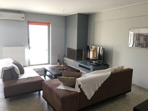 A living room with a brown sofa, a coffee table, and a flat-screen TV on a stand. - Cozy Flat With Acropolis View (Athens)