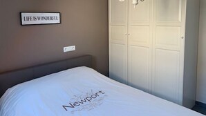 A bedroom with a bed, a chandelier, a wardrobe, and a sign on the wall. - Noorderbries 404 (Nieuwpoort)