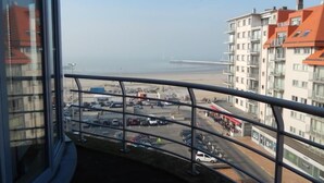 A balcony with a view of a beach, a parking lot, and adjacent buildings. - Zeezicht 604 (Nieuwpoort)