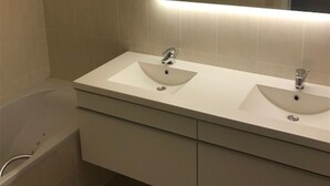 A bathroom with two sinks, a mirror, and a bathtub. - Zeezicht 604 (Nieuwpoort)