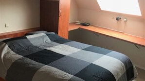A single bed with a checkered bedspread in a room with wooden flooring, a slanted ceiling, and a skylight. - Zeezicht 604 (Nieuwpoort)