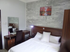 A hotel room with a bed, a desk, a chair, a mirror, a painting, and a wardrobe. - Vintage Nest (Ota)