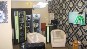 Habitación de hotel con minibar, televisión, dos sillones y un papel tapiz estampado.