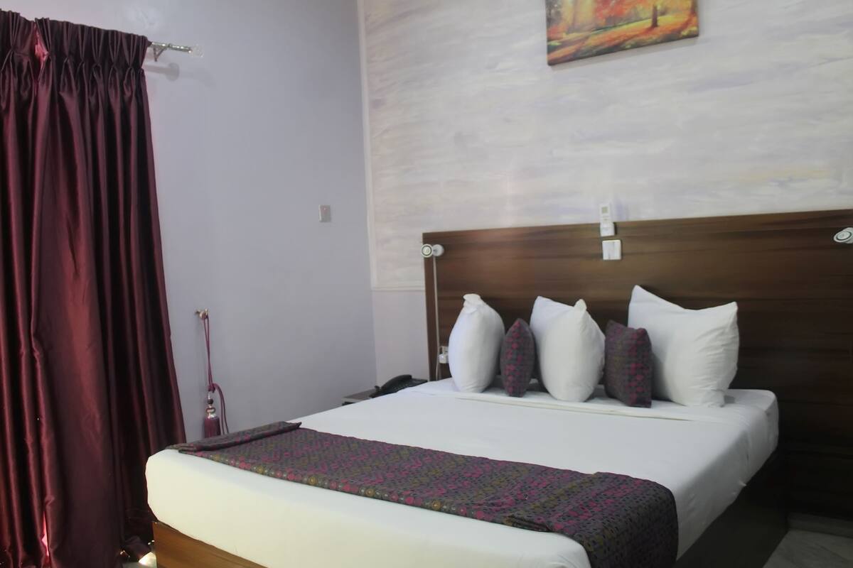 A hotel room with a large bed, a wooden headboard, and a painting on the wall.
