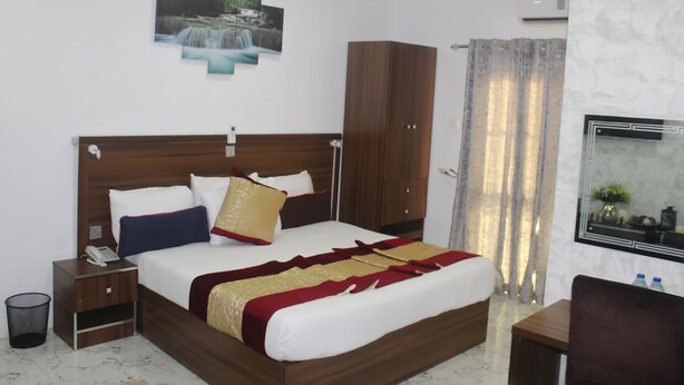 Un dormitorio ordenado con una cama de madera, una mesita de noche, un teléfono, una obra de arte en la pared, un armario y un espejo.