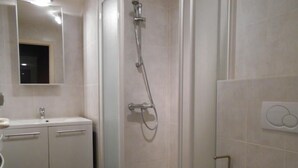 A bathroom with a glass-enclosed shower, a white sink, and a toilet. - Cezanne (Nieuwpoort)