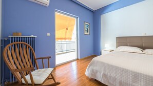 A bedroom with a bed, a wooden rocking chair, a radiator, and a window with a view. - Comfortable Apartment near City Center (Athens)