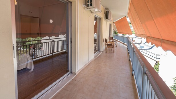 A balcony with a wooden floor, air conditioning units, and a view of the street. - Comfortable Apartment near City Center (Athens)