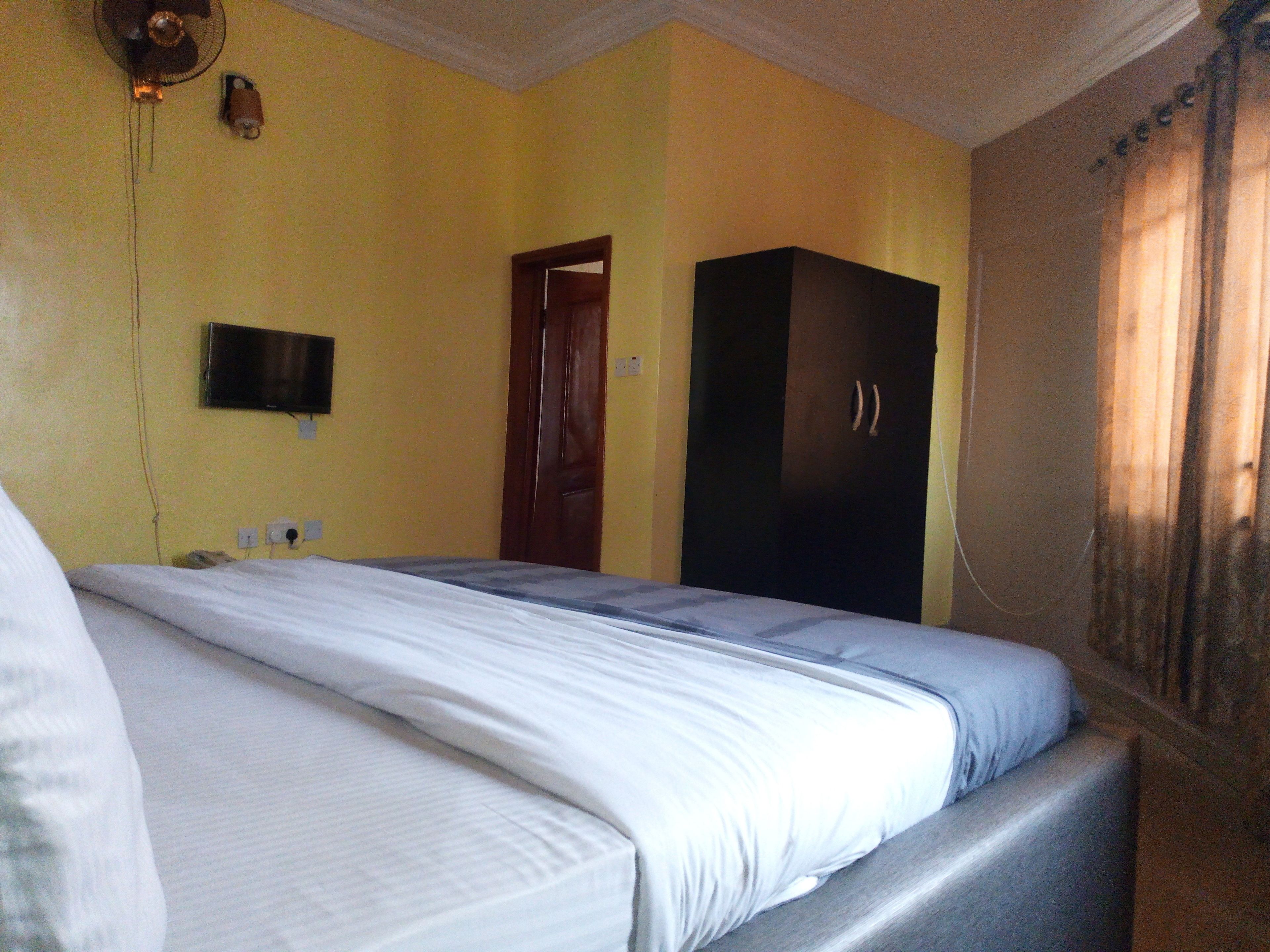Una habitación de hotel con una cama, un armario, un televisor y una puerta.