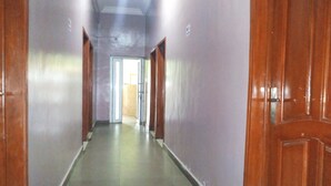 Un pasillo largo y estrecho con puertas de madera a ambos lados, que desemboca en una habitación luminosa al final.