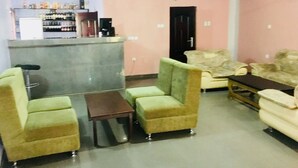 Una habitación con sofá, sillones, una mesita y una zona de bar con estanterías.