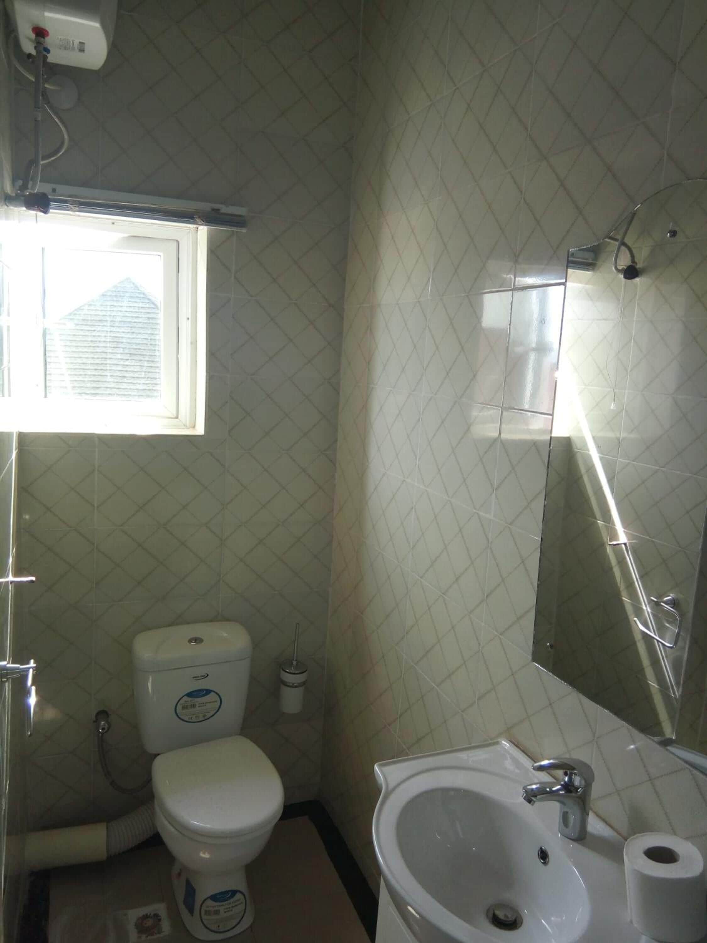 Ein kleines Badezimmer mit Toilette, Waschbecken und Fenster.