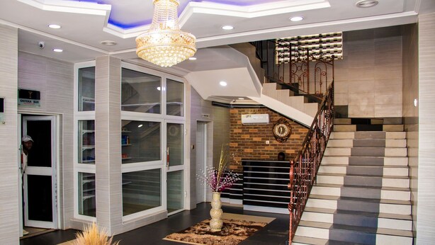 En moderne lobby med trappe, lysekrone og reception.