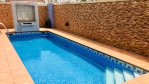 A rectangular swimming pool with blue tiles and a tiled deck.
