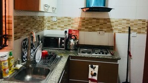 A kitchen with a gas stove, a microwave, a sink, and a dish rack.