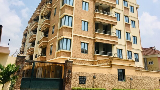 A multi-story residential building with balconies, a gated entrance, and a sign indicating it is a residential complex.
