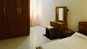 Quarto com cama, guarda-roupa de madeira, penteadeira com espelho e ar condicionado na parede.