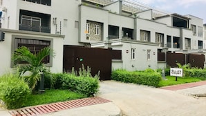 Um edifício residencial moderno com várias varandas, entrada com portão e uma placa indicando 'Ella's Court'.