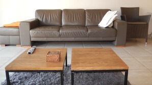 A living room with a grey sofa, a wooden coffee table, a wicker basket, and a remote control. - Zeezicht 201 (Nieuwpoort)