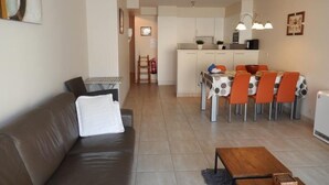 A modern living room with a sofa, a wooden coffee table, and a dining area with a table and chairs. - Zeezicht 201 (Nieuwpoort)