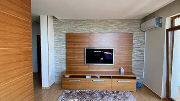 Un salon moderne avec un téléviseur à écran plat fixé à un meuble mural en bois, un tapis à motifs et un canapé en cuir.
