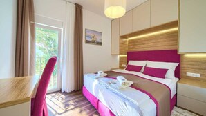 Hotellihuone, jossa on sänky, työpöytä, tuoli, ikkuna verhoilla ja seinään kiinnitetty lamppu.