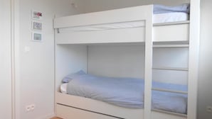 Uma cama beliche com um beliche inferior e um beliche superior, ambos com roupa de cama branca.