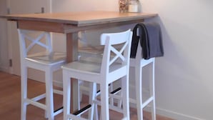 Uma sala de jantar com uma mesa de madeira e duas cadeiras brancas.