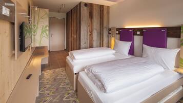 Habitación de hotel con dos camas, un televisor y una pared de acento de madera.