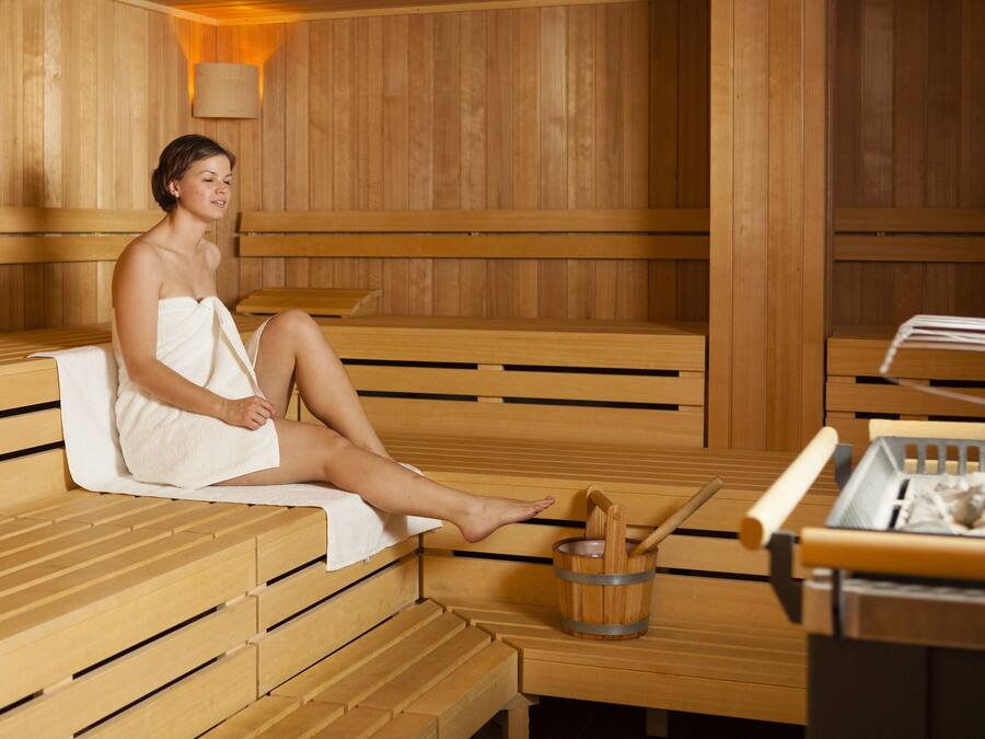 A sauna with wooden benches and a wooden bucket with a brush.