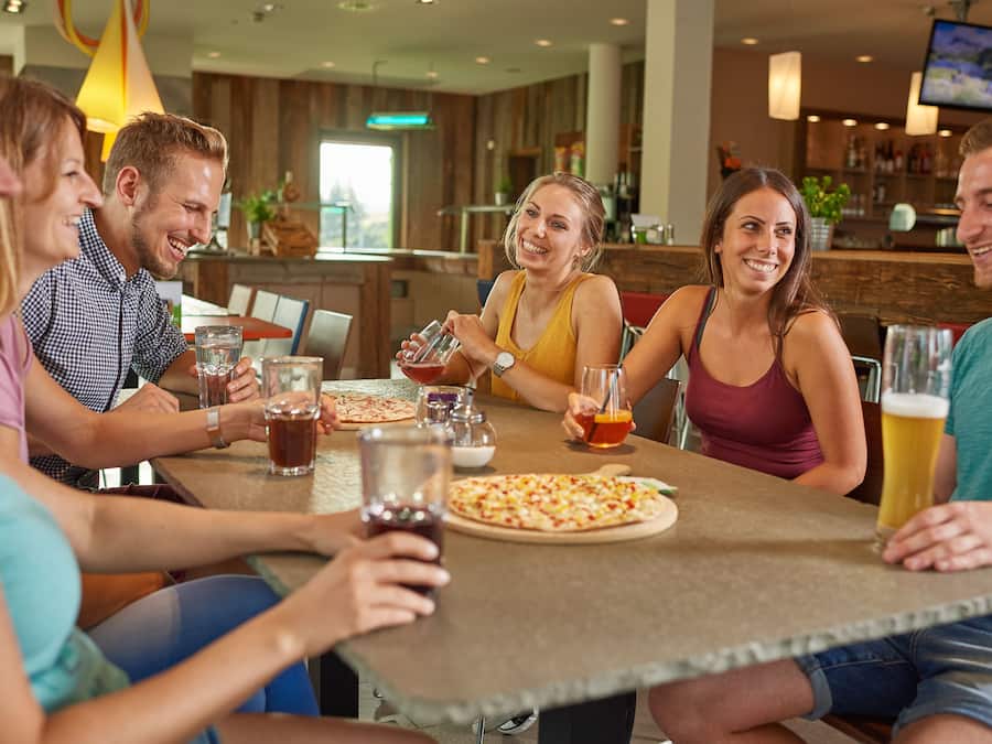 Un grupo de personas sentadas alrededor de una mesa con bebidas y pizza.