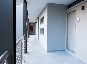 A modern hallway with a metal railing, a fire extinguisher, and a door marked with the number 6.