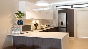 A modern kitchen with a central island, bar stools, a refrigerator, and a potted plant. - Hydepark Executive (Randburg)