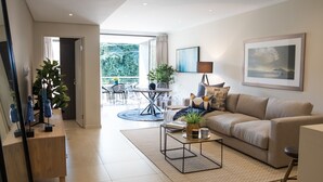 A modern living room with a sofa, coffee table, and a dining area with chairs and a table. - Hydepark Executive (Randburg)
