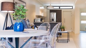 A modern dining area with a round table, clear chairs, a floor lamp, and a potted plant. - Hydepark Executive (Randburg)