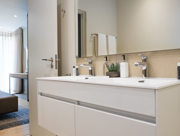 Une salle de bain moderne avec un meuble-lavabo à deux vasques, un miroir et une plante en pot.