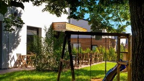 A playground with swings and a slide, surrounded by a grassy area and trees. - Penzion Dílna (Trebon)