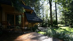 Een houten hut met een terras, omringd door dicht bos.