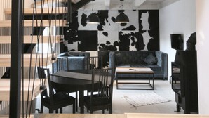 Een modern interieur met een trap, houten vloer en een eethoek met een tafel en stoelen.