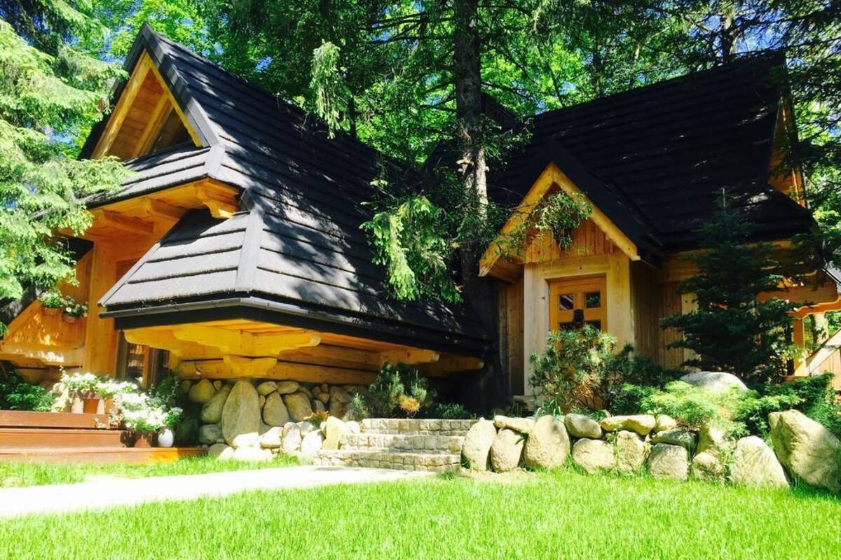 Une cabane dotée d’un toit en pente, de fondations en pierre et d’une pelouse bien entretenue.