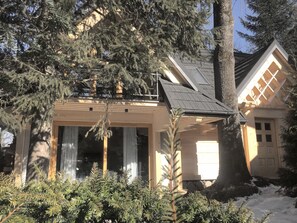 Una casa con techo inclinado, ventanas grandes y una chimenea visible.