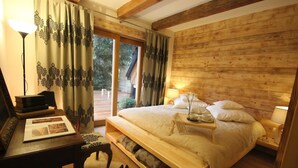 Een slaapkamer met houten lambrisering, een bed, nachtkastje, lamp en uitzicht op de omgeving.